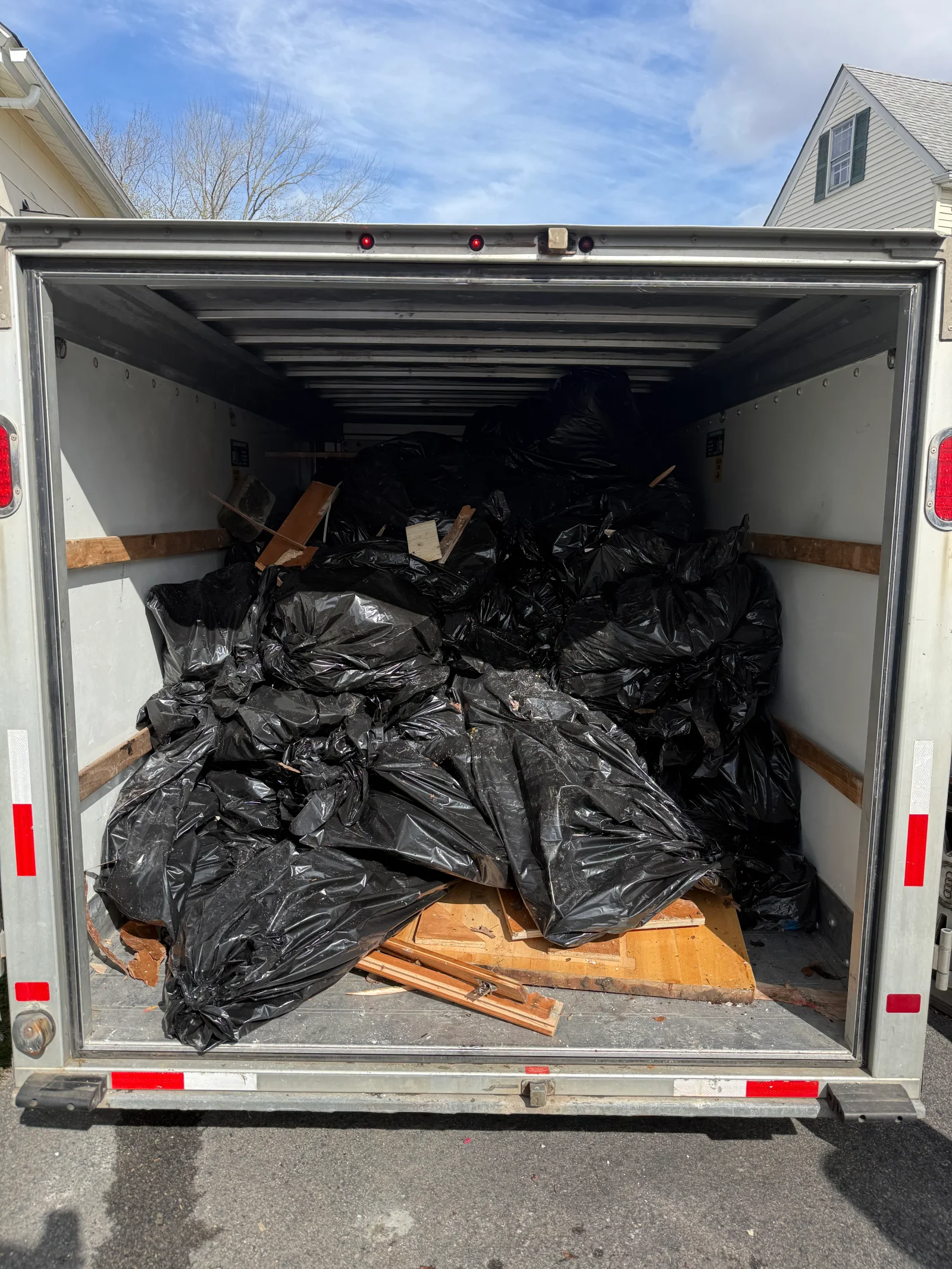 Box truck loaded with black trash bags, plywood sheets, and wood scrap during a junk removal job